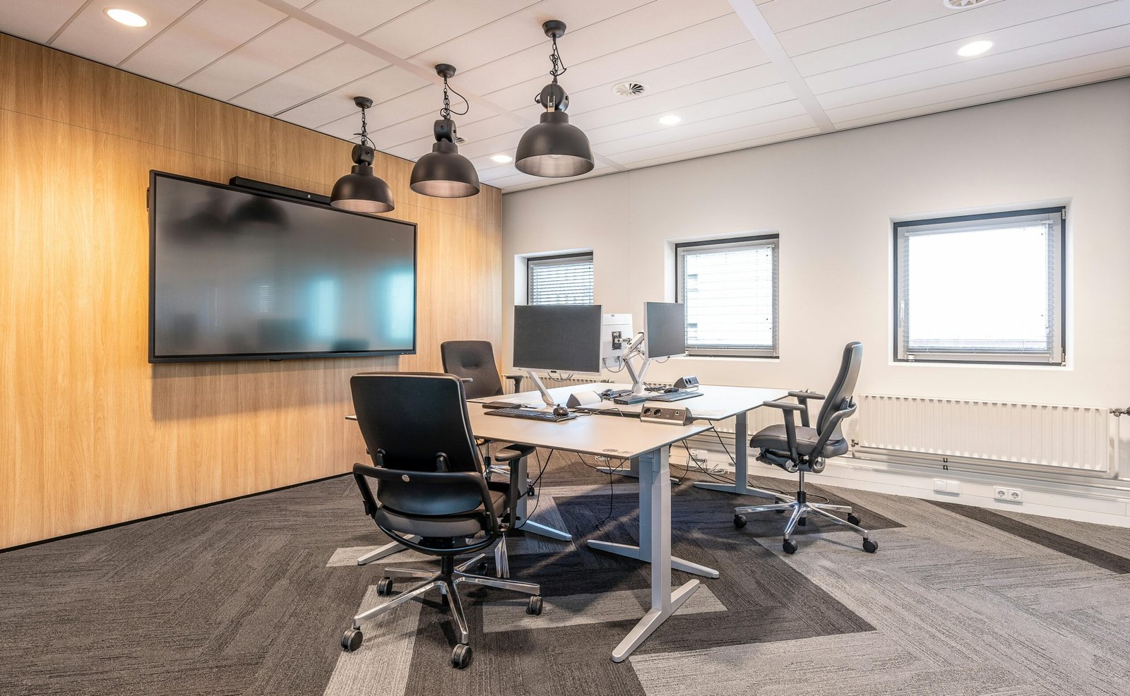 Spacious, well-lit office conference room featuring modern computers and a large screen display for presentations.